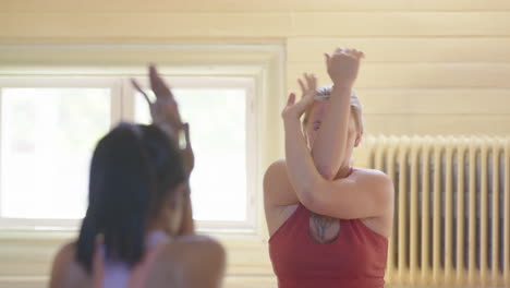 Female-yoga-instructor-demonstrates-eagle-pose-gripping-palm-and-thumb-in-yoga-class