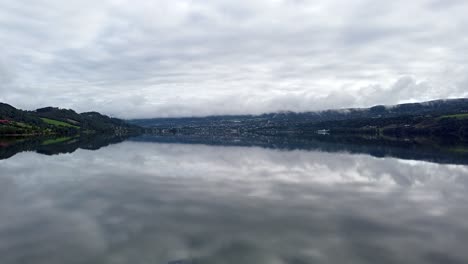 Drohnenaufnahmen-Eines-Ruhigen-Sees-In-Norwegen,-Die-Den-Bewölkten-Himmel-Und-Die-Umgebende-Landschaft-Widerspiegeln