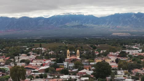 Luftaufnahme-Einer-Drohne-Von-Gebäuden-In-Der-Altstadt-Von-Cafayate,-Salta,-Argentinien,-Mit-Der-Andenkordillere-Im-Hintergrund