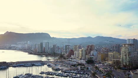 Spanische-Küstenstadt-Calpe,-Blick-Aus-Der-Vogelperspektive-Mit-Wunderschönem-Sonnenuntergang-Hinter-Den-Bergen