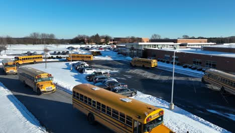 Elementary-school-children-boarding-yellow-school-buses-to-go-home-on-snowy-day