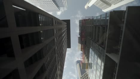 Dynamic-car-POV-shot-looking-up-at-skyscrapers-and-a-construction-crane-against-a-clear-sky