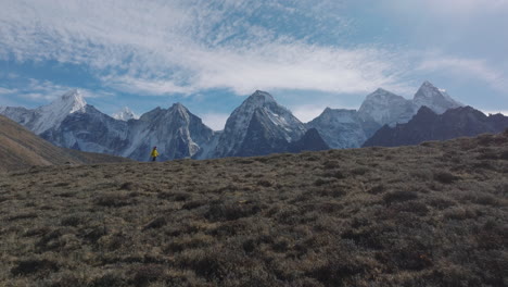 A-revealing-drone-shot-of-a-male-trekker-at-Everest-Base-Camp,-Nepal,-admiring-the-majestic-mountain-views