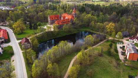 Medieval-Cesvaine-Castle-in-aerial-Approaching-View-with-Castle-Grounds-and-Pond-in-sight