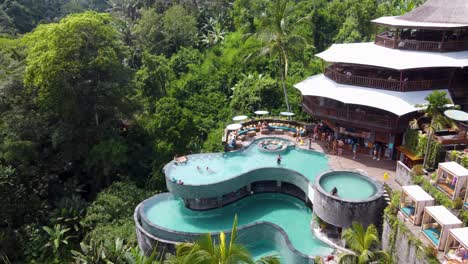 People-relaxing-by-the-Pool-at-Cretya-Jungle-Day-Club-in-Ubud-Bali,-Drone-Reveal