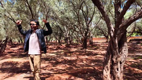 Moroccan-tour-guide-explaining-to-tourists-inside-olive-tree-garden,-Morocco