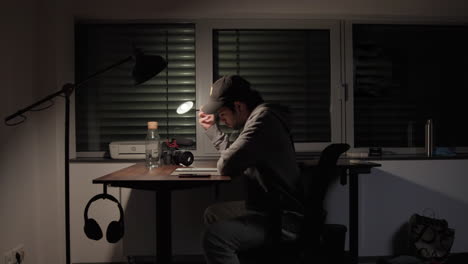 Young-Man-Sitting-At-A-Desk-Thinking,-Wide-Shot