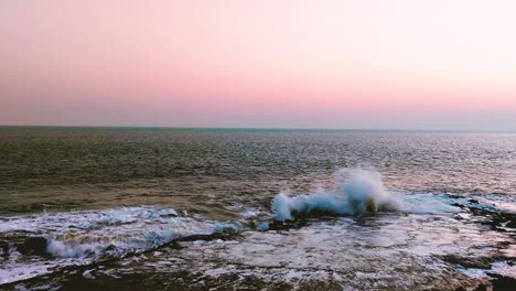 Olas-De-Agua-De-Playa-Golpeando-Piedras-Grandes,-Al-Atardecer