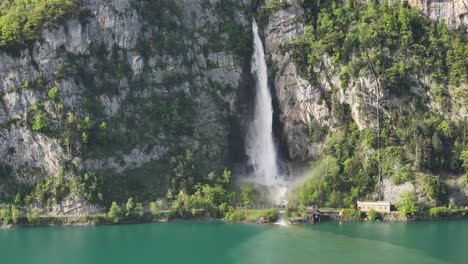 Seerenbach-Falls-cascading-down-a-steep-cliff-into-a-turquoise-lake,-surrounded-by-lush-greenery,-in-Amden,-Betlis,-near-Walensee,-Switzerland