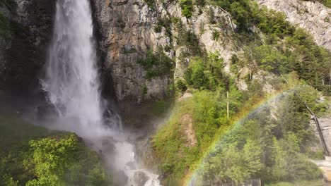 Close-up-view-of-Seerenbach-Falls-with-a-rainbow-in-the-mist,-cascading-down-a-cliff-surrounded-by-lush-greenery-in-Amden,-Betlis,-near-Walensee,-Switzerland