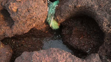 Lava-rock-formations-with-colorful-mineral-deposits-and-water-flow,-close-up