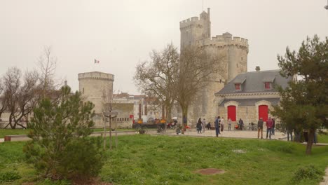 Turistas-Explorando-Las-Torres-Históricas-De-La-Rochelle-Durante-La-Mañana-Brumosa-En-Francia.