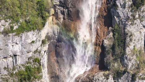 Seerenbach-Falls-with-a-vibrant-rainbow-in-the-mist,-cascading-down-a-rugged-cliff-in-Amden,-Betlis,-near-Walensee,-Switzerland