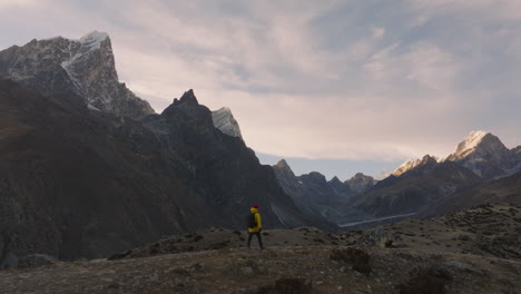 Un-Dron-Captura-A-Un-Excursionista-En-El-Campamento-Base-Del-Everest-En-Nepal,-Disfrutando-De-Las-Majestuosas-Vistas-De-Las-Montañas-Durante-La-Puesta-De-Sol-De-La-Hora-Dorada.