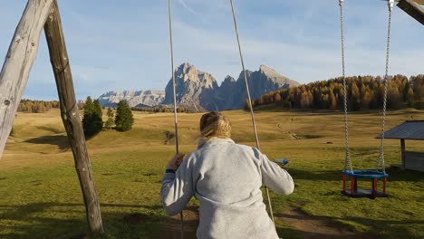 Blonde-Frau-Streckt-Die-Beine-Aus-Und-Lehnt-Sich-Zurück,-Während-Sie-Schaukelt-Und-Die-Ruhige-Landschaft-Italiens-Bewundert