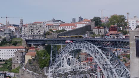 Porto-subway-on-a-sunny-day-crossinf-Dom-Luis-I-Bridge-in-Porto,-with-tourists-walking,-wide-view