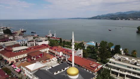 Aerial-shot-of-Batumi-Mosque-close-by-the-coast-of-the-black-sea-with-road-and-cars-passing-by