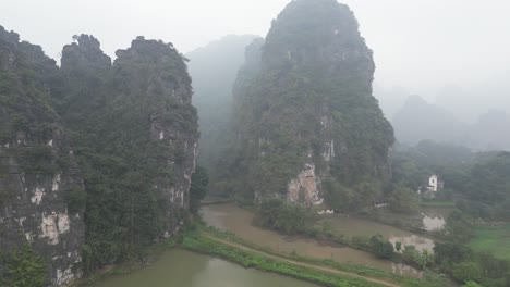 drone-shot-of-dramatic-cliffs-surrounded-by-water-in-the-mountainous-region-of-Ninh-Ninh-in-Northern-Vietnam