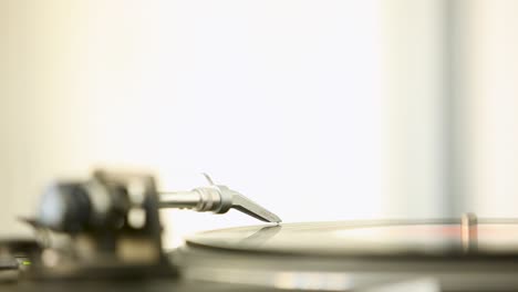 Close-up-of-a-hand-placing-the-needle-on-a-vinyl-record-in-a-bright-room