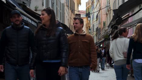 People-walking-by-boutiques-on-narrow-street-in-Cannes,-France,-during-the-day