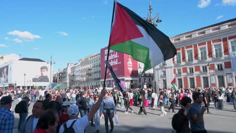 During-a-pro-Palestine-demonstration-in-Madrid,-Spain,-a-protester-waves-a-Palestinian-flag,-urging-the-Spanish-government-to-halt-arms-sales-to-Israel