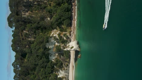 Motorboat-in-Cathedral-Cove-Marine-Reserve,-north-Island-New-Zealand---vertical-aerial