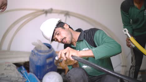 Engineer-in-green-uniform-and-white-hard-hat-working-on-machinery-in-a-Pakistani-factory