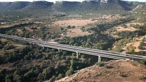 Busy-Italian-rural-highway-traffic-crossing-scenic-ravine-viaduct-drone-shot