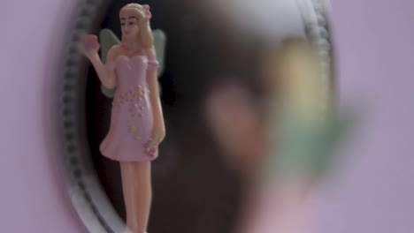 Close-up-of-a-spinning-figurine-in-a-music-box,-focused-on-a-delicate-doll-in-a-pink-dress-against-a-blurred-background