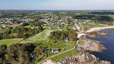 A-coastal-village-with-houses,-trees,-and-a-rocky-shoreline,-aerial-view