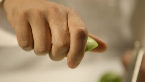 Close-up-of-a-hand-squeezing-lime-juice,-focus-on-the-dripping-lime,-soft-background