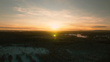 Colorful-winter-sunset,-drone-push-in-over-forest-in-Sweden