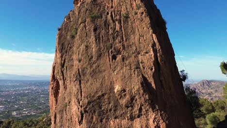 Man-rock-climbing-aerial-view-of-sportsman-rapelling-mountain-in-La-Panocha,-el-Valle-Murcia,-Spain-woman-rapel-down-a-mountain-climbing-a-big-rock