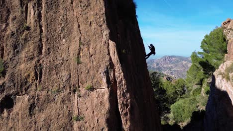 Man-rock-climbing-aerial-view-of-sportsman-rapelling-mountain-in-La-Panocha,-el-Valle-Murcia,-Spain-woman-rapel-down-a-mountain-climbing-a-big-rock