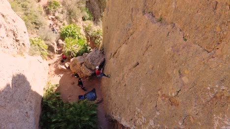 Man-rock-climbing-aerial-view-of-sportsman-rapelling-mountain-in-La-Panocha,-el-Valle-Murcia,-Spain-woman-rapel-down-a-mountain-climbing-a-big-rock