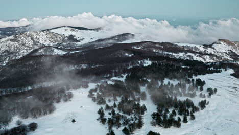 Paisaje-Montañoso-Cubierto-De-Nieve-Con-Bosques-Brumosos-Y-Nubes-Espectaculares