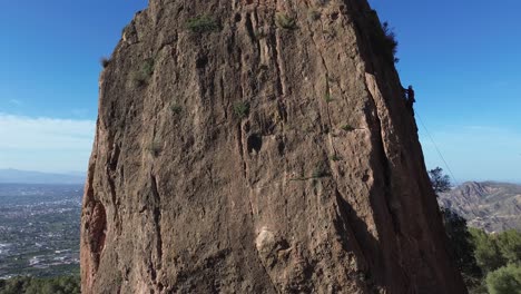 Man-rock-climbing-aerial-view-of-sportsman-rapelling-mountain-in-La-Panocha,-el-Valle-Murcia,-Spain-woman-rapel-down-a-mountain-climbing-a-big-rock