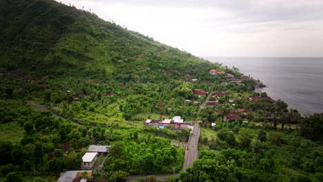 Paisaje-Panorámico-Aéreo-De-Un-Pueblo-Costero-De-Montaña-Con-Gasolinera-En-Amed,-Bali,-Indonesia.