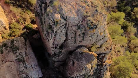 Man-rock-climbing-aerial-view-of-sportsman-rapelling-mountain-in-La-Panocha,-el-Valle-Murcia,-Spain-woman-rapel-down-a-mountain-climbing-a-big-rock