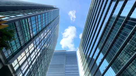 Looking-up-at-modern-skyscrapers-against-a-bright-blue-sky-with-scattered-clouds