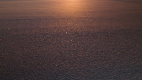 Low-altitude-drone-push-in-over-snow-bed,-Nora,-Sweden