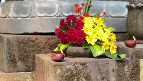 Kerzen-Und-Blumen-Auf-Der-Steinoberfläche-Im-Indonesischen-Kloster