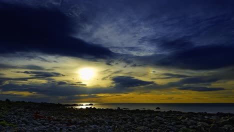 Steinstrand-Und-Meer-In-Der-Hellen-Nacht-Mit-Den-Wolken,-Die-Sich-In-Richtung-Mitternachtssonne-Bewegen