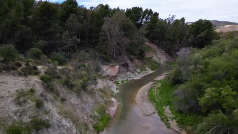 Mountain-river-valley-with-sandy-slopes-in-Estepona,-aerial-ascend-view