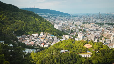 Vista-Panorámica-De-Una-Ciudad-Enclavada-Entre-Exuberantes-Colinas-Verdes,-Que-Muestra-Una-Mezcla-De-Edificios-Residenciales-Y-Paisajes-Naturales.-Un-Amplio-Horizonte-Con-Un-Cielo-Despejado,-Destacando-La-Mezcla-Urbana-Y-Rural.