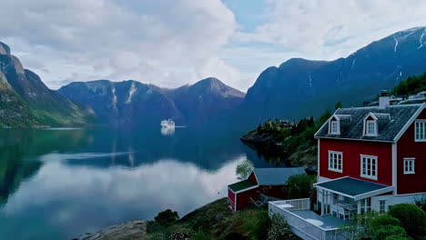 Vista-Panorámica-De-Aurland,-Noruega,-Con-Una-Casa-Roja-Junto-Al-Fiordo-Y-Las-Montañas-Al-Fondo