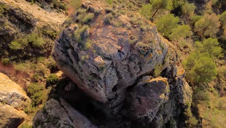 Man-rock-climbing-aerial-view-of-sportsman-rapelling-mountain-in-La-Panocha,-el-Valle-Murcia,-Spain-woman-rapel-down-a-mountain-climbing-a-big-rock