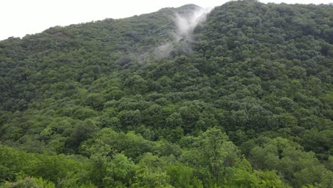 Aerial-view-of-fog-mountains-village-country-road-in-beautiful-green-meadows-mountains