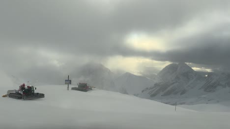 Snowplows-clearing-fresh-snow-on-Zugspitze-with-mountains-in-the-background,-cloudy-day