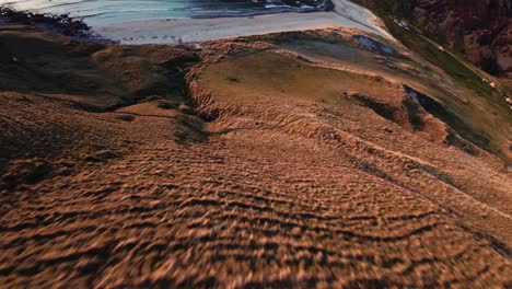 FPV-fly-down-mountain-slope-during-golden-hour-in-Hoddevik,-Norway